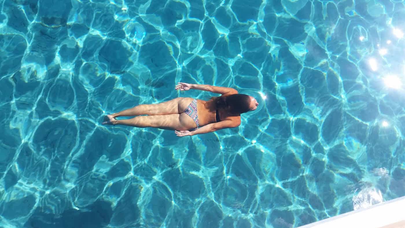 Alquiler catamaran Ibiza día. Chica nadando en aguas turquesas.