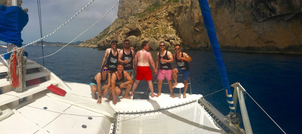 Enterrement de vie de garçon sur un catamaran à Ibiza, des garçons sur la proue du catamaran. L'un d'eux sur son dos avec la marque du T-shirt.