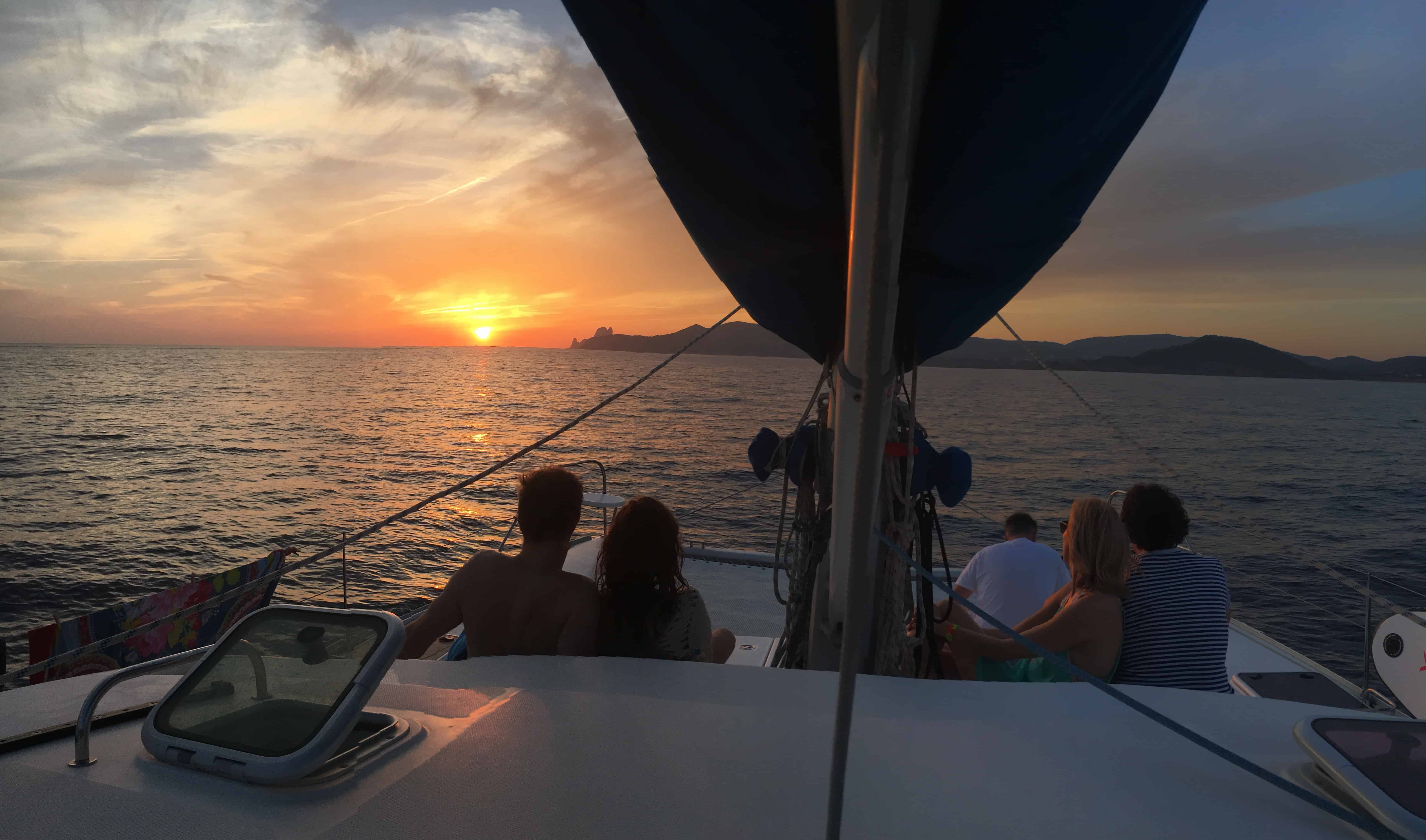 Excursión en catamaran Ibiza y Formentera, grupo en proa admirando la puesta de sol