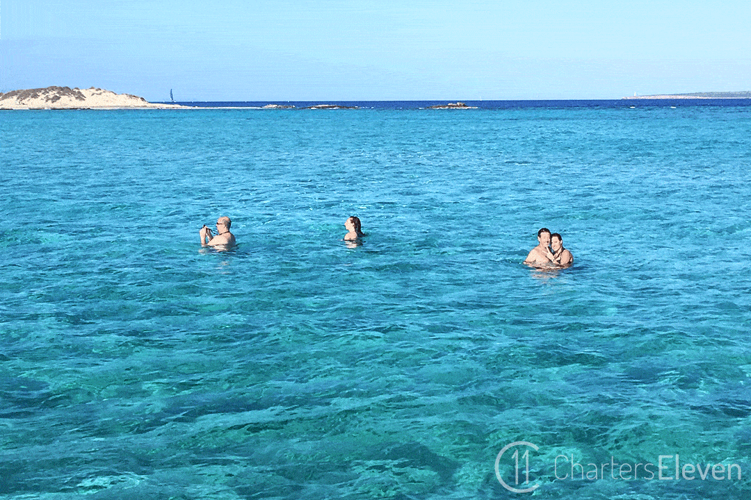 Un groupe d'amis se tient dans l'eau tout près de notre catamaran.