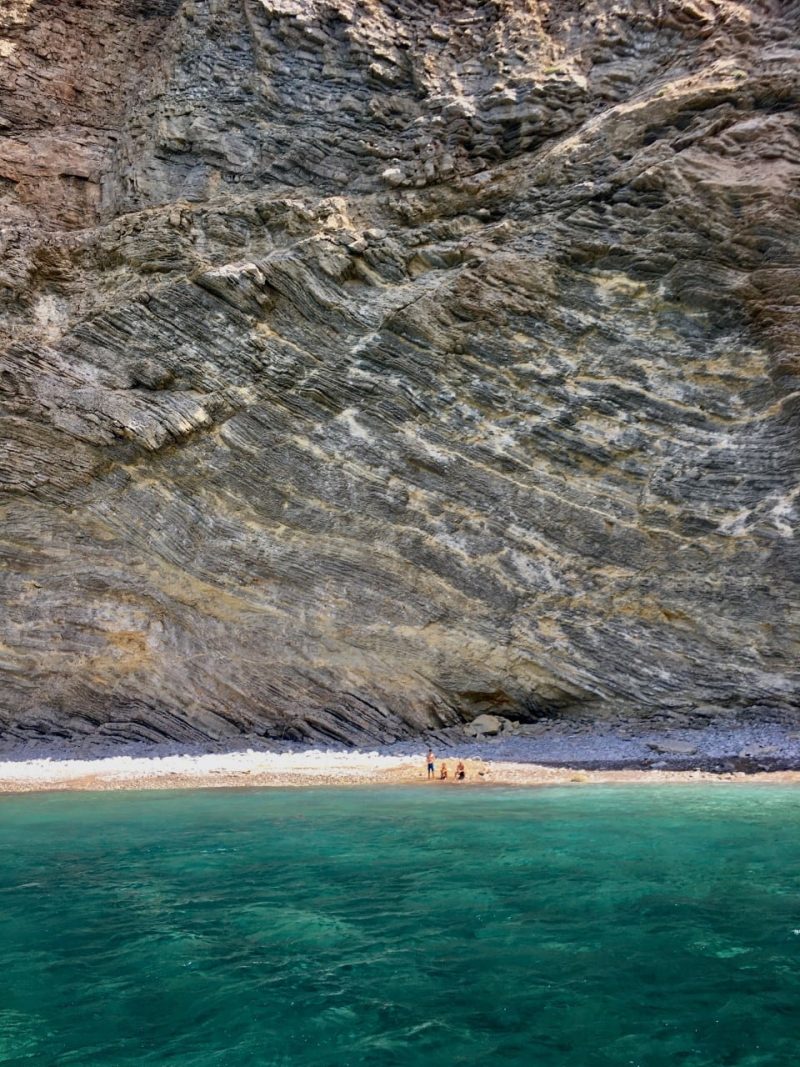 family on a small beach underneath a stunning cliff