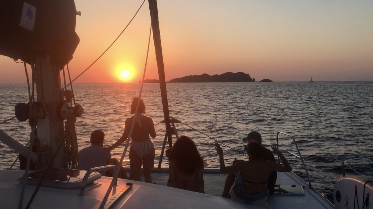un groupe d'amis profitant du coucher de soleil en catamaran à Ibiza